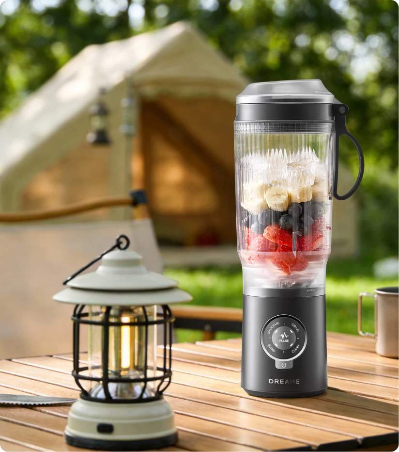 Dreame Portable Blender che frulla frutta fresca all'aperto durante un campeggio per bevande sane