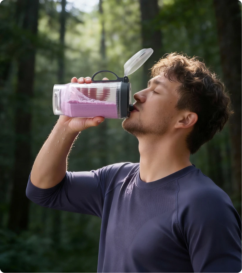 Utente che beve uno smoothie dal bicchiere portatile Dreame Portable Blender durante un'escursione nel bosco