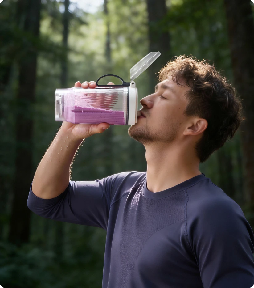 Utente che beve uno smoothie dal bicchiere portatile Dreame Portable Blender durante un'escursione nel bosco