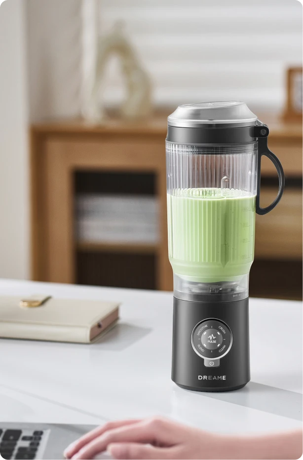 Dreame Portable Blender design senza fili su una scrivania in ufficio che mescola una bevanda verde durante il lavoro